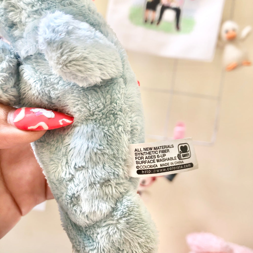 Angled view of Colorata manatee plush keychain with teal ball chain