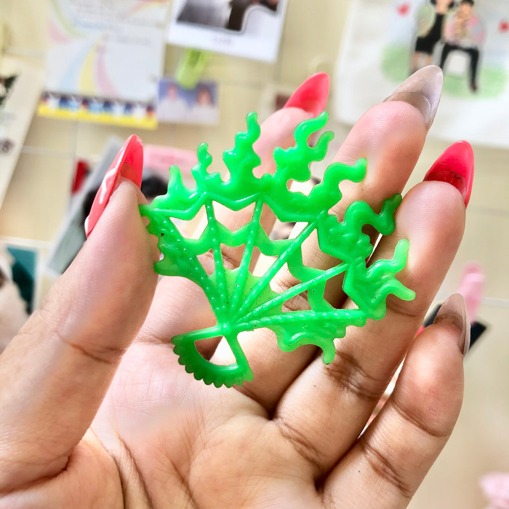 Front view of neon green Monster High spiderweb accessory held in hand