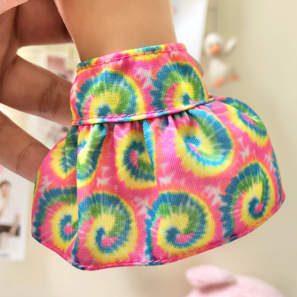 Front view of colorful tie-dye mini skirt on doll showing rainbow swirl pattern