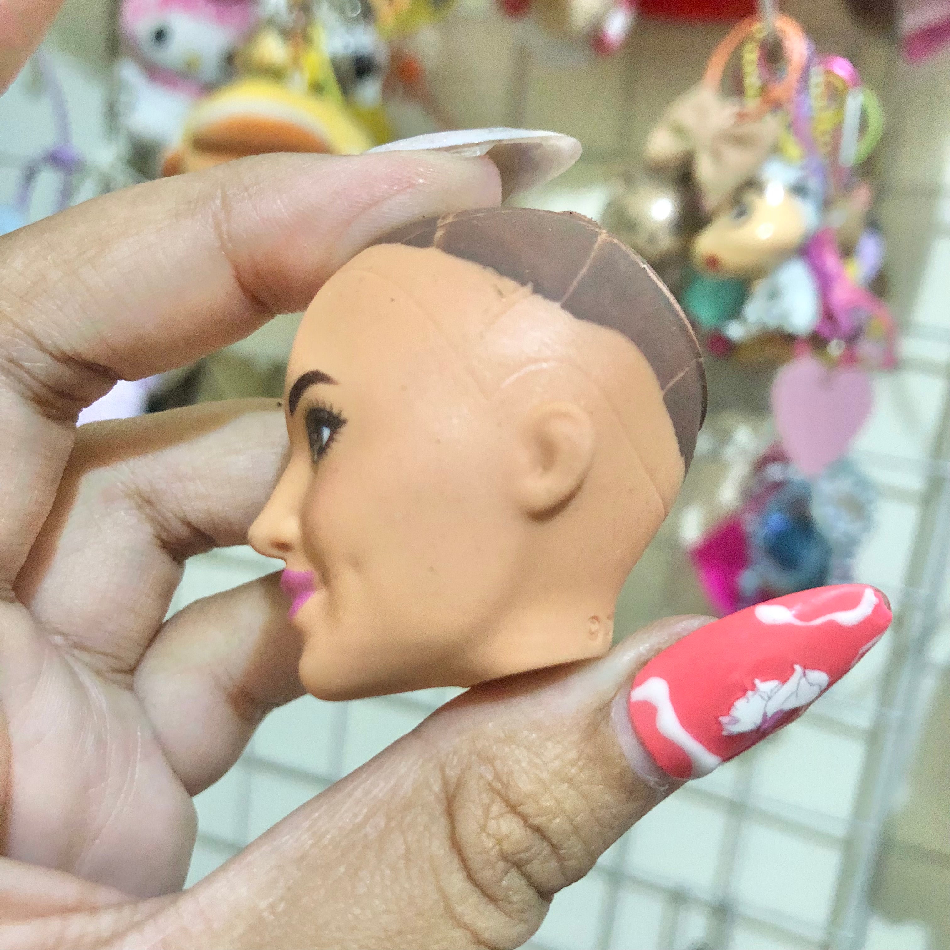 Barbie factory sample bald doll head front view showing brown eyes and iridescent lips