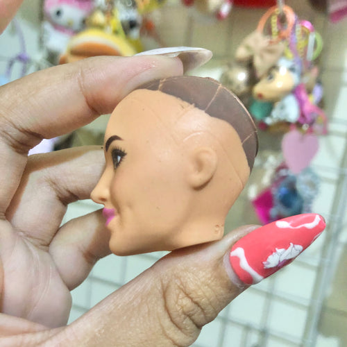 Barbie factory sample bald doll head front view showing brown eyes and iridescent lips
